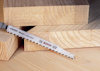 Sågblad märkt "Bosch Expert Wood 2-side clean" mot träbitar.