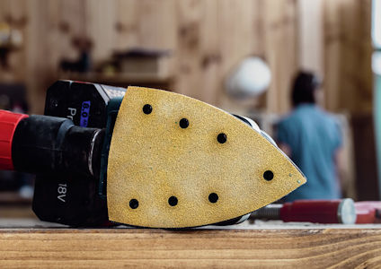 Slippapper på en slipmaskin, liggande på ett trädäck med suddig bakgrund.