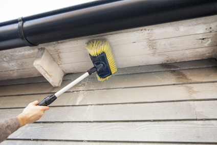 Gul borste på skaft används för att rengöra träfasad och takutsprång.