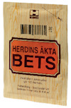Förpackning av Herdins Äkta Bets, med träliknande design och texten "Vattenlöslig - God ljusäkthet".