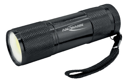 Svart ficklampa med text "ANSMANN" på sidan, utrustad med handledsrem.