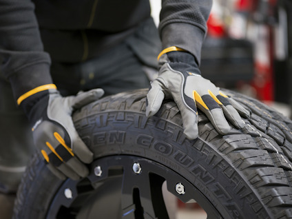 Händer i skyddshandskar vidrör däck med texten "OPEN COUNTRY".