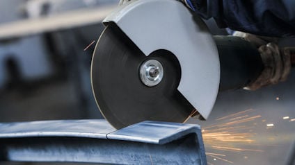 Vinkelslip som skär genom metall, gnistor flyger åt sidan.