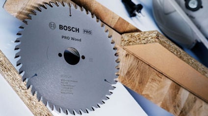 Cirkelsågblad av märket Bosch Pro Wood, omgiven av trästycken.