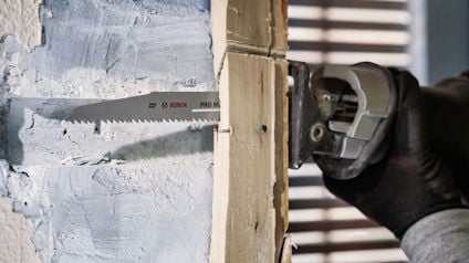 Person sågar i en trävägg med en elektrisk såg.