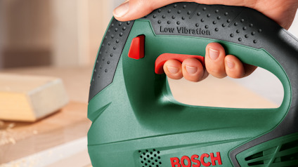 En person håller i ett grönt Bosch-verktyg med texten "Low Vibration".