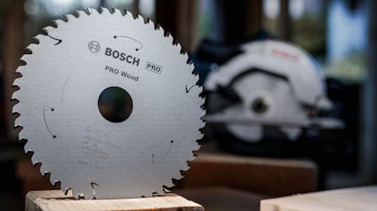 Cirkelsågklinga med texten "BOSCH PRO Wood" på en träyta, bakgrund med oskarp såg.