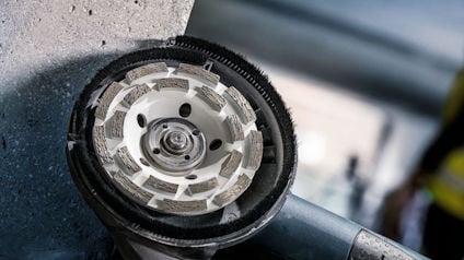 Diamantslipskiva fräser en betongyta med en vinkelslipmaskin i en industriell miljö.