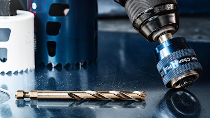 Borr, borrchuck och två hålsågar på metallisk yta.