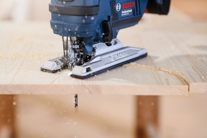 Sticksåg från Bosch Professional i användning på en träplanka, med träspån som sprutar omkring.