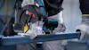 Elektrisk cirkelsåg som skär genom en metallbalk, opererad av person med skyddshandskar.