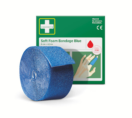 Blå skumförbandsrulle framför en grön förpackning märkt "Soft Foam Bandage Blue, 6 cm x 4,5 m".