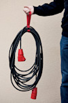 En person håller en svart elkabel med röda kontakter i en röd bärrem.