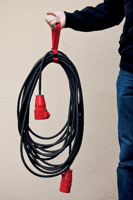 En person håller en svart elkabel med röda kontakter i en röd bärrem.