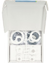 Vit kartong med öppet lock innehållande cirkelformade plastdelar i vitt och transparent material.